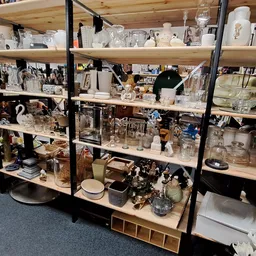 Stellingen vol met huishoudelijke artikelen, glaswerk, servies en decoratieve items