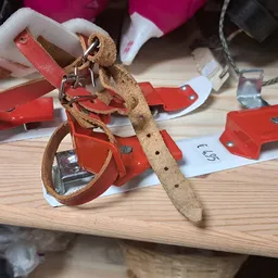 Close-up van een tweedehands leren riem met gesp en rode verpakkingslabels op houten tafel