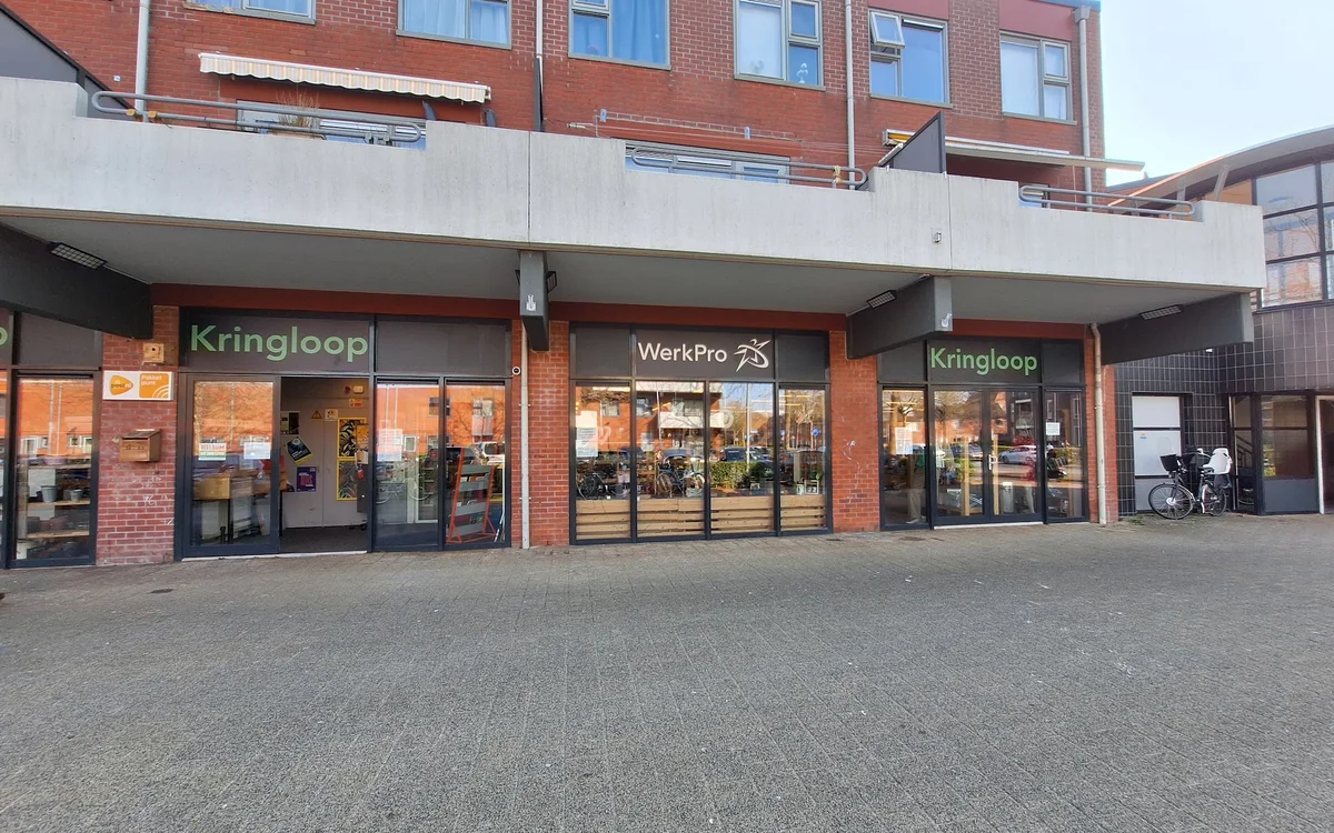 Gevel van kringloopwinkel met rode bakstenen, uitstalkramen en winkelnaam zichtbaar