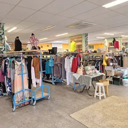 Overzicht van de winkelvloer met kledingrekken, uitgestalde tweedehands kleding en diverse artikelen