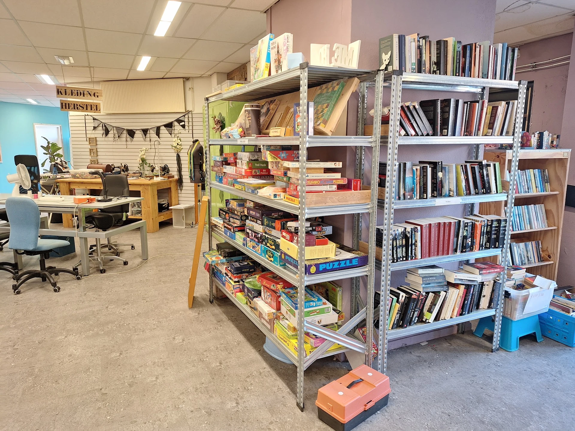 Winkelvloer met metalen stellingen vol boeken, een werkplek links en decoratie aan het plafond