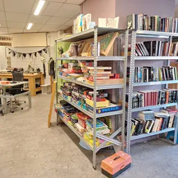 Winkelvloer met metalen stellingen vol boeken, een werkplek links en decoratie aan het plafond
