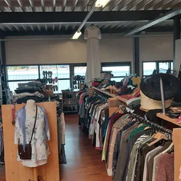Winkelvloer met kledingrekken en spullen uitgestald in een kringloopwinkel