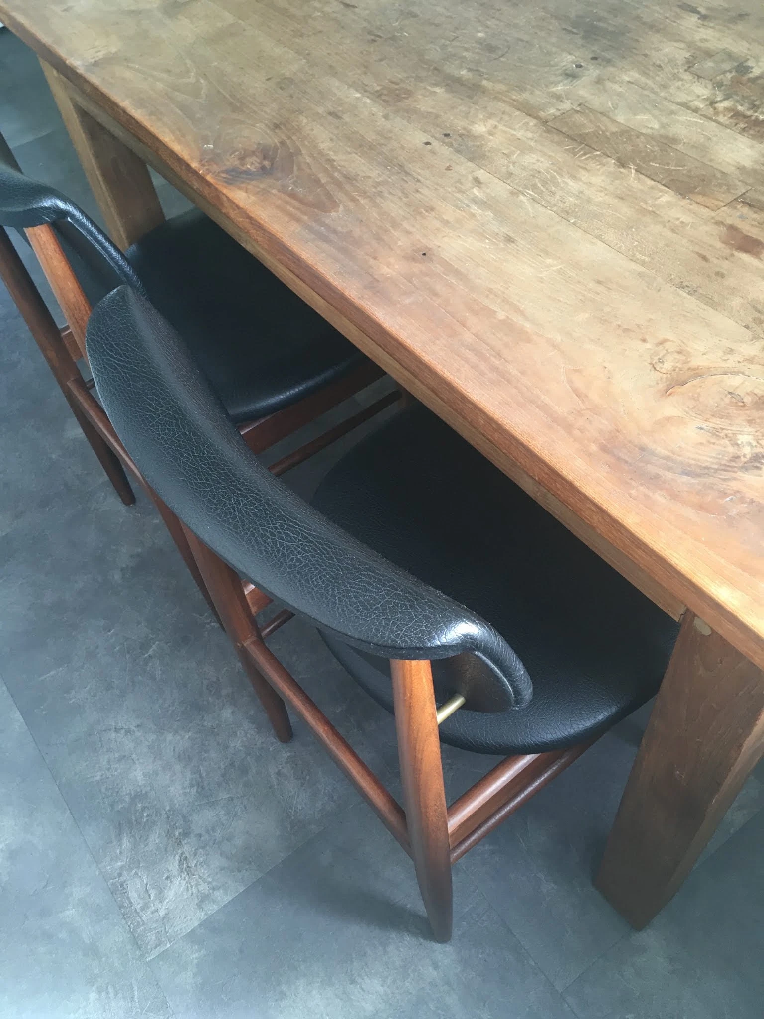 Zwarte lederen stoel met houten poten naast houten tafel
