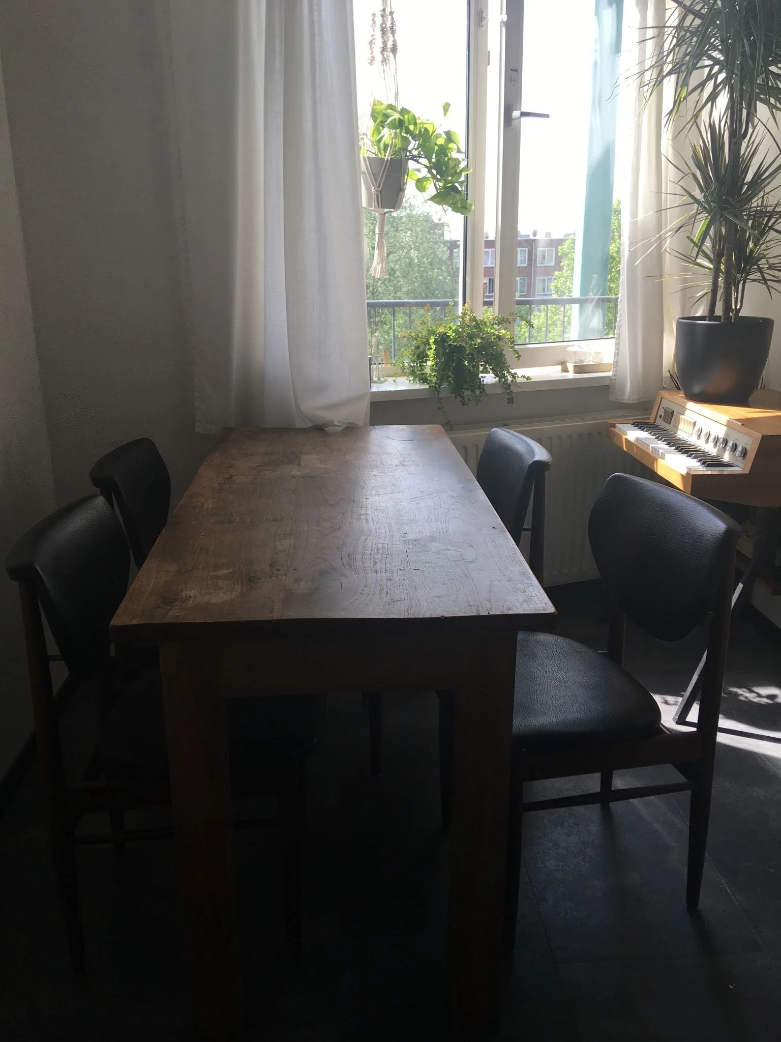 Donker houten eettafel met zwarte stoelen in een kantoorachtig interieur met raam
