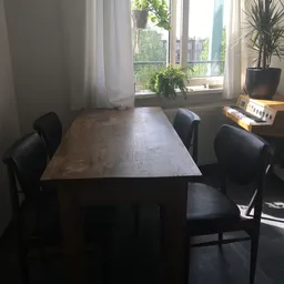 Donker houten eettafel met zwarte stoelen in een kantoorachtig interieur met raam