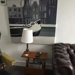 Tafellamp met witte plissékap en houten voet op een bruin tafeltje