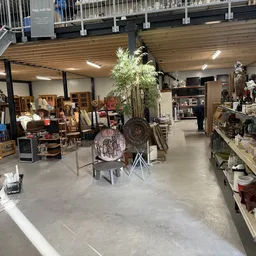 Ruim interieur van kringloopwinkel met diverse meubelen, decoratie en spullen op stellingen en inDisplayruimtes