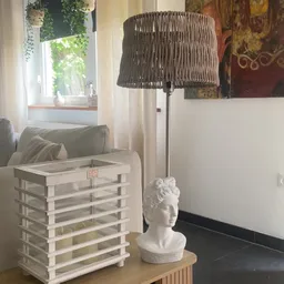 Witte bustehouder met ronde sculptuur en staande lamp met rieten kap in interieur