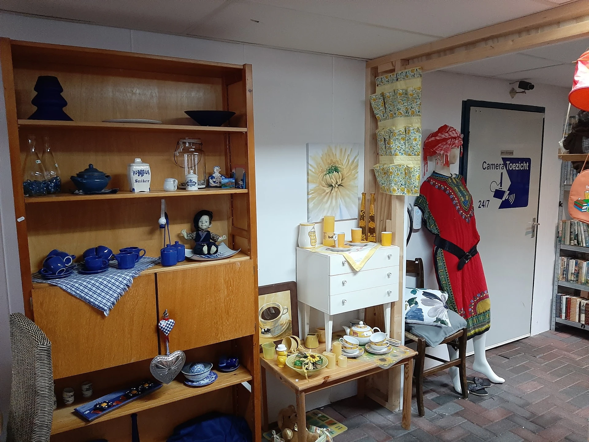 Winkelvloer met houten vitrinekasten, vintage meubels en diverse huishoudelijke spullen uitgestald
