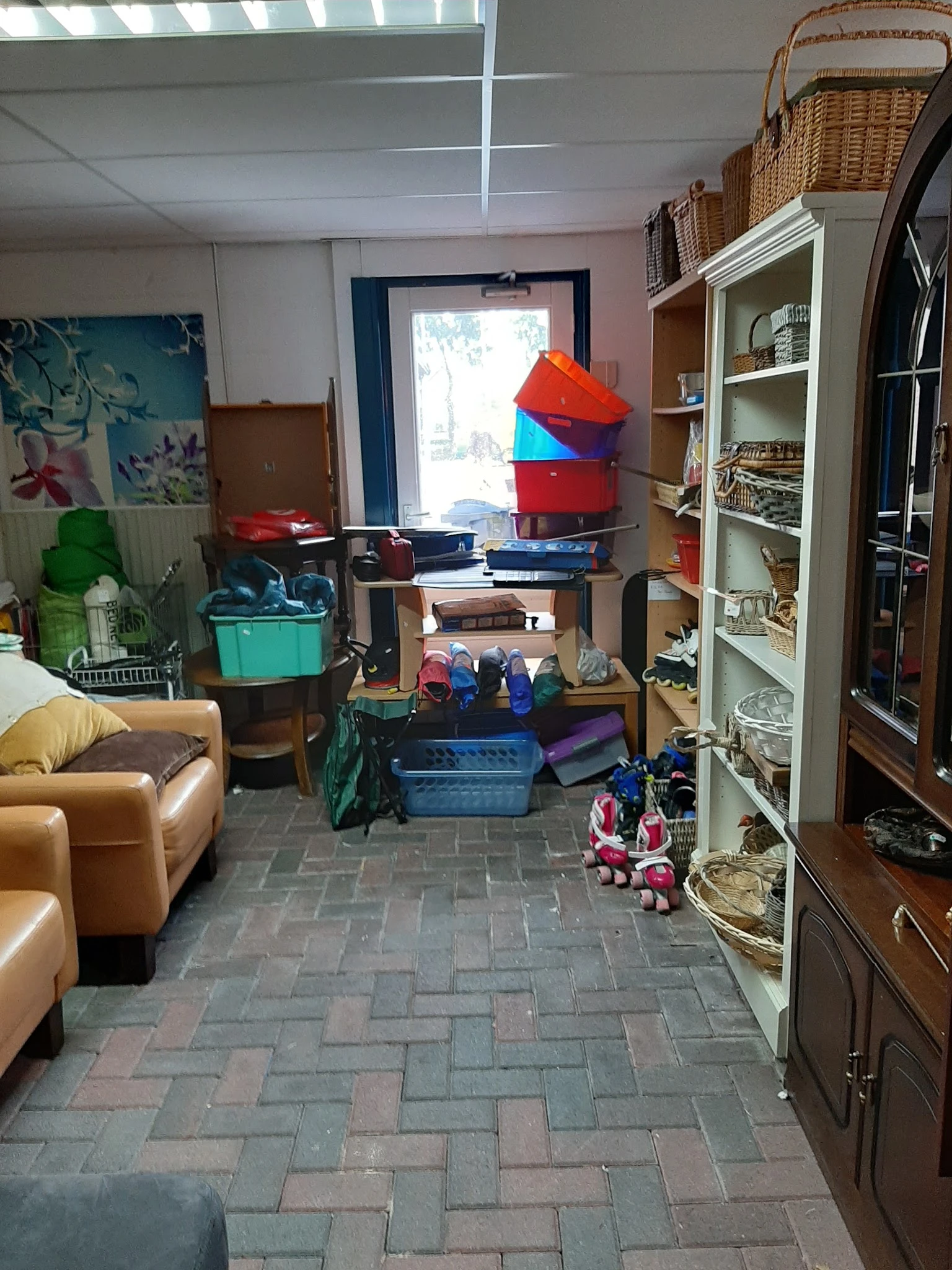 Winkelinterieur met stellingen, opgestapelde dozen, speelgoed, meubels en diverse tweedehandsartikelen