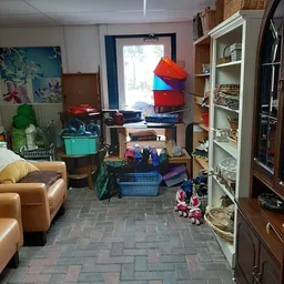 Winkelinterieur met stellingen, opgestapelde dozen, speelgoed, meubels en diverse tweedehandsartikelen
