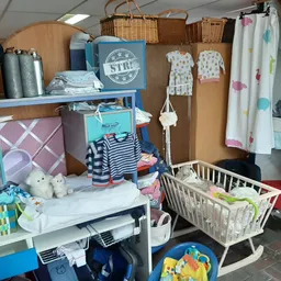 Babykamer spullen en kinderaccessoires: ledikantje, verschoontafel, speelgoed en textiel op stellingen