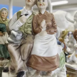 Porseleinbeeldje van een vrouw in bruine en witte kledij met hoofddoek