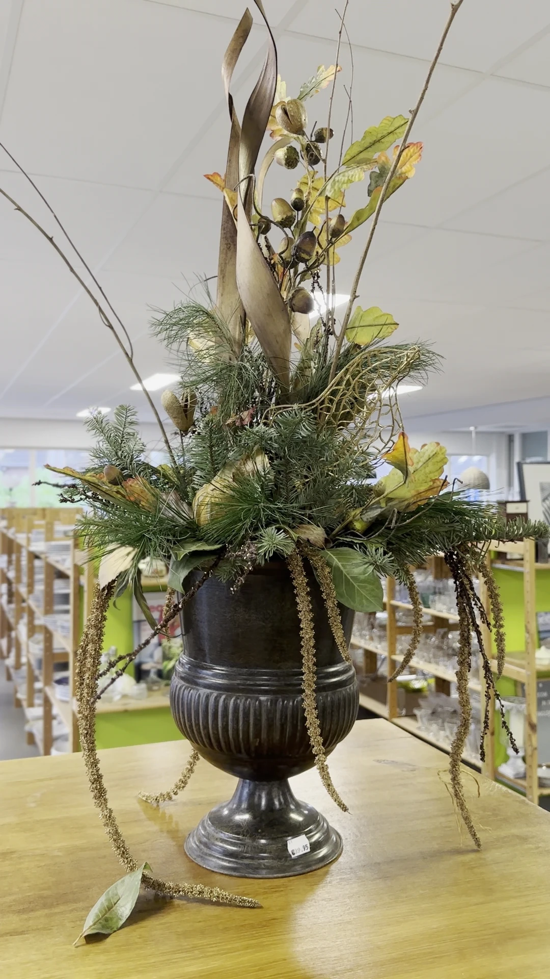Zwarte pot met arrangement van groene planten en gele bloemen