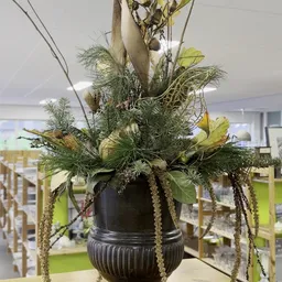 Zwarte pot met arrangement van groene planten en gele bloemen
