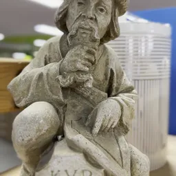 Close-up van een stenen beeld van een zittend figuur met gedetailleerde gezichtsuitdrukking