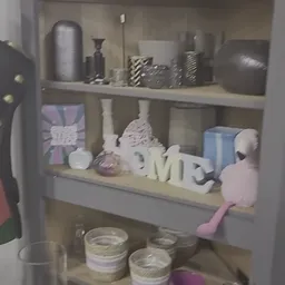 Opzet van decoratieve items op een plank met witte letters, vazen, roze figuren en diverse huishoudartikelen