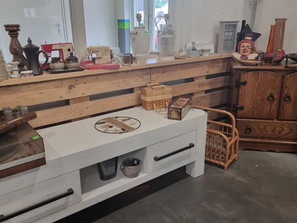 Winkelvloer met houten toonbank, witte kast, vintage spullen en houten meubels langs de muur