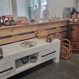 Winkelvloer met houten toonbank, witte kast, vintage spullen en houten meubels langs de muur