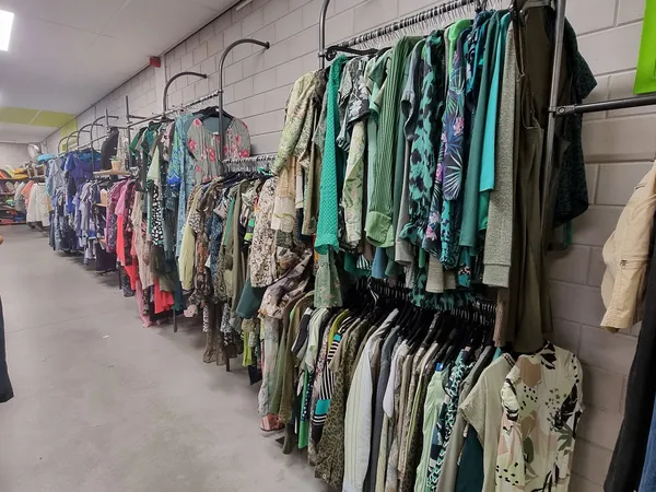Lange rijen kledingrekken met tweedehands kleding in verschillende kleuren en stijlen