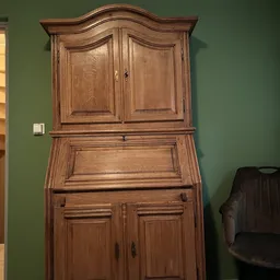 Houten secretaire met twee deuren bovenaan en uitgeklapt schrijfblad, tegen groene muur