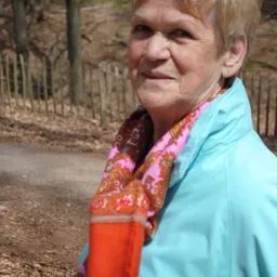 Persoon in lichtblauwe jas met kleurrijke sjaal buiten bij een kringloopwinkel