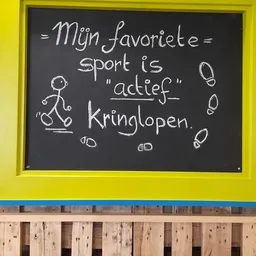 Schoolbord met handgeschreven Nederlandse tekst over favoriete sport 'actief kringlopen'