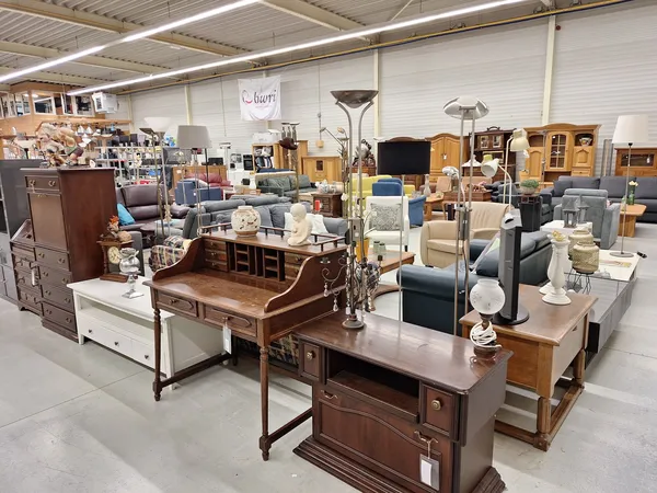 Winkelinterieur met meubelen: tafels, stoelen, kasten en overige huisraad uitgestald in een groot magazijnachtig pand