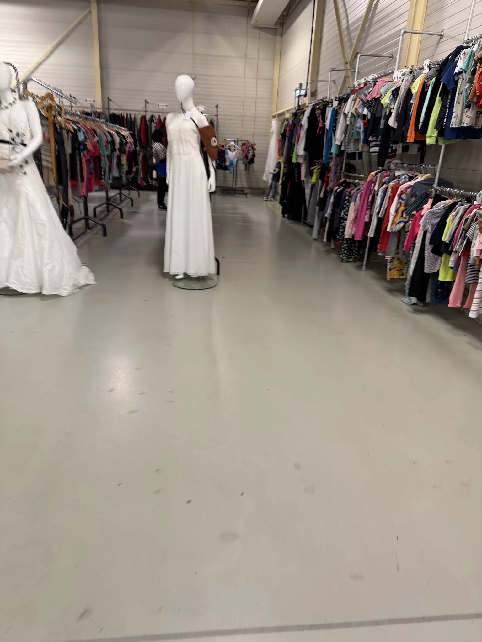 Winkelvloer met rekken vol kleding aan beide zijden, witte jurken op display