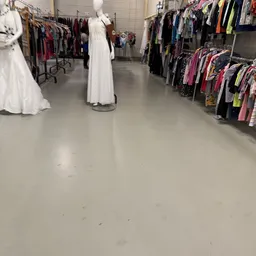 Winkelvloer met rekken vol kleding aan beide zijden, witte jurken op display