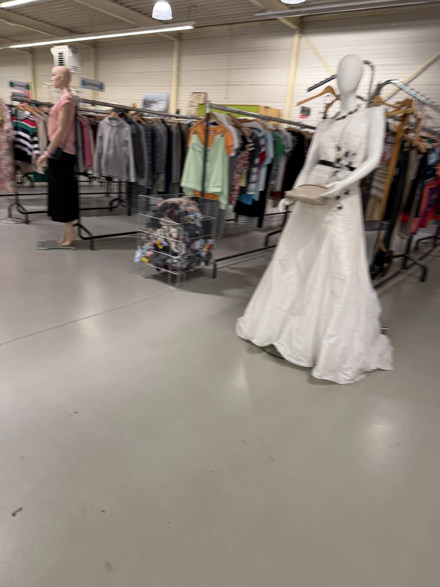 Witte jurk en ander textiel op hangers in de winkel