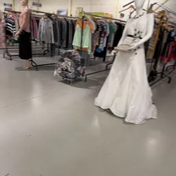 Witte jurk en ander textiel op hangers in de winkel
