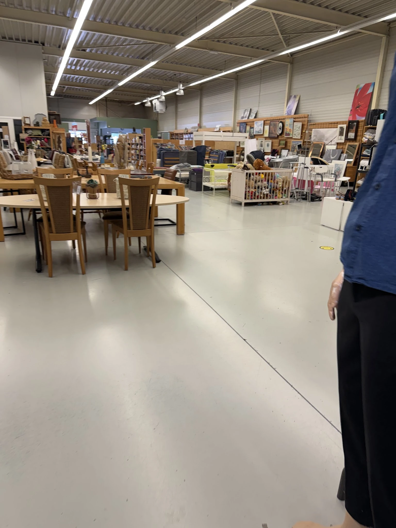 Winkelvloer met houten tafels, stoelen en stellingen met tweedehands spullen