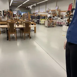 Winkelvloer met houten tafels, stoelen en stellingen met tweedehands spullen