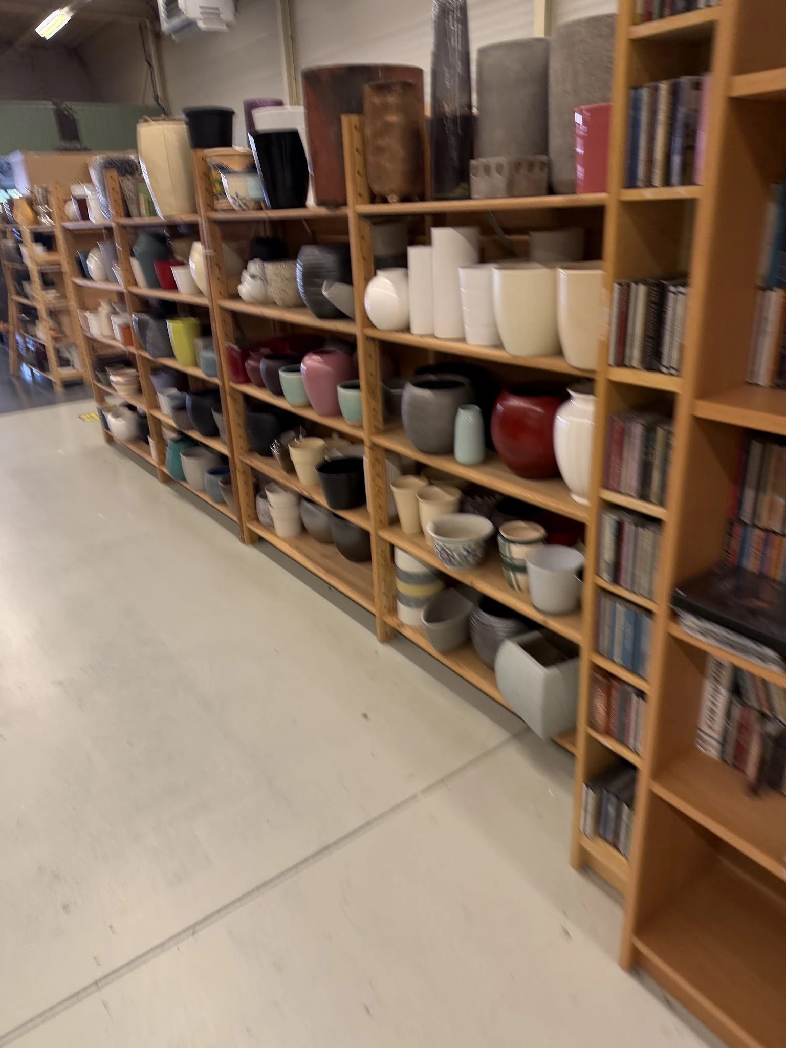Houten stellingen met diverse huishoudelijke artikelen, waaronder witte en gekleurde plastic bakken en dozen op verschillende