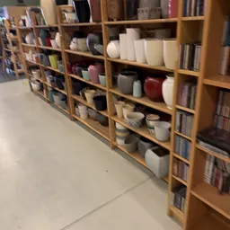 Houten stellingen met diverse huishoudelijke artikelen, waaronder witte en gekleurde plastic bakken en dozen op verschillende