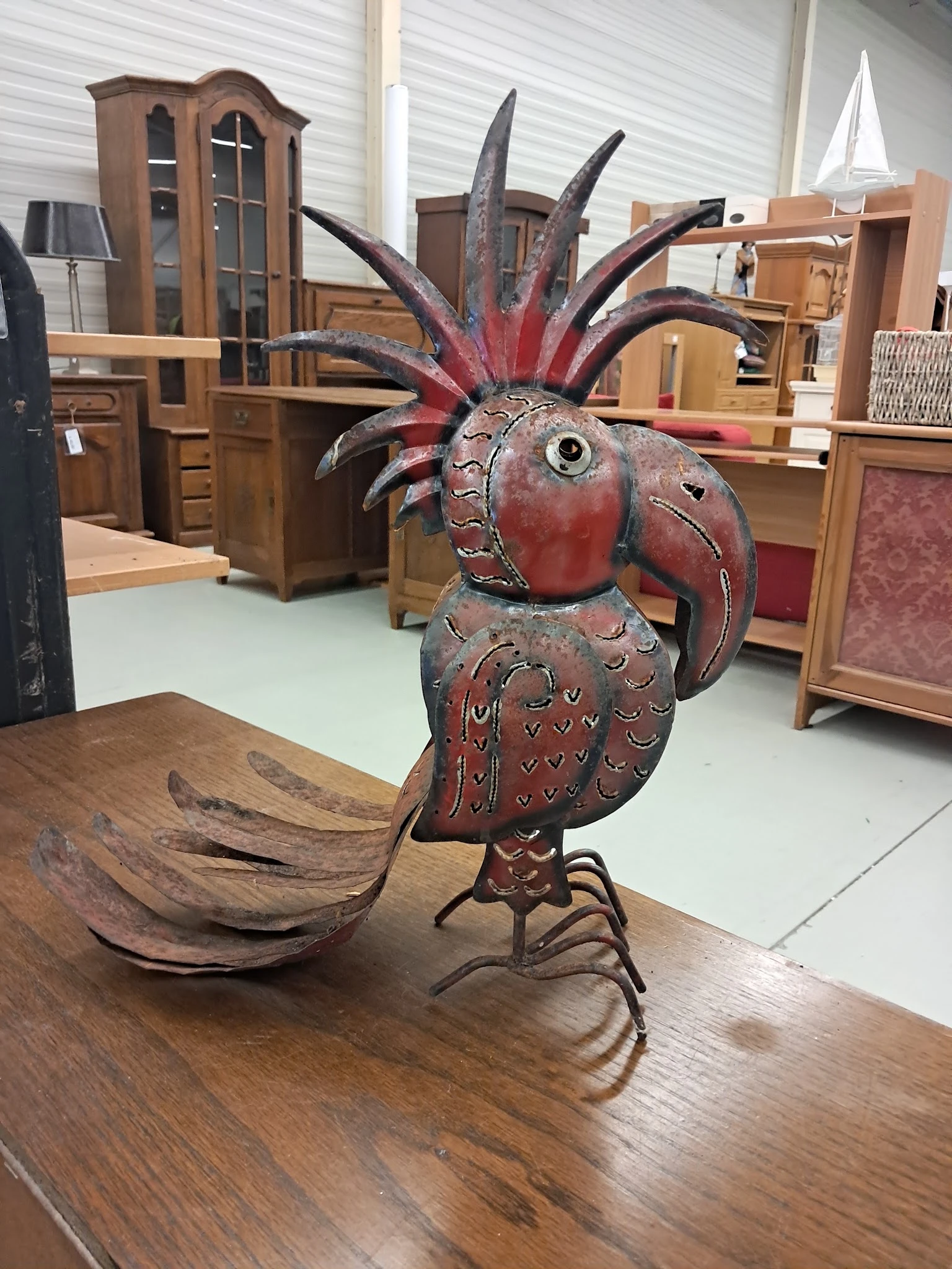 Rood-bruine decoratieve houten vogel met uitstaande veren op een tafel in de winkel