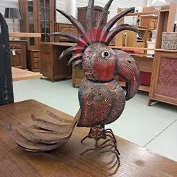 Rood-bruine decoratieve houten vogel met uitstaande veren op een tafel in de winkel