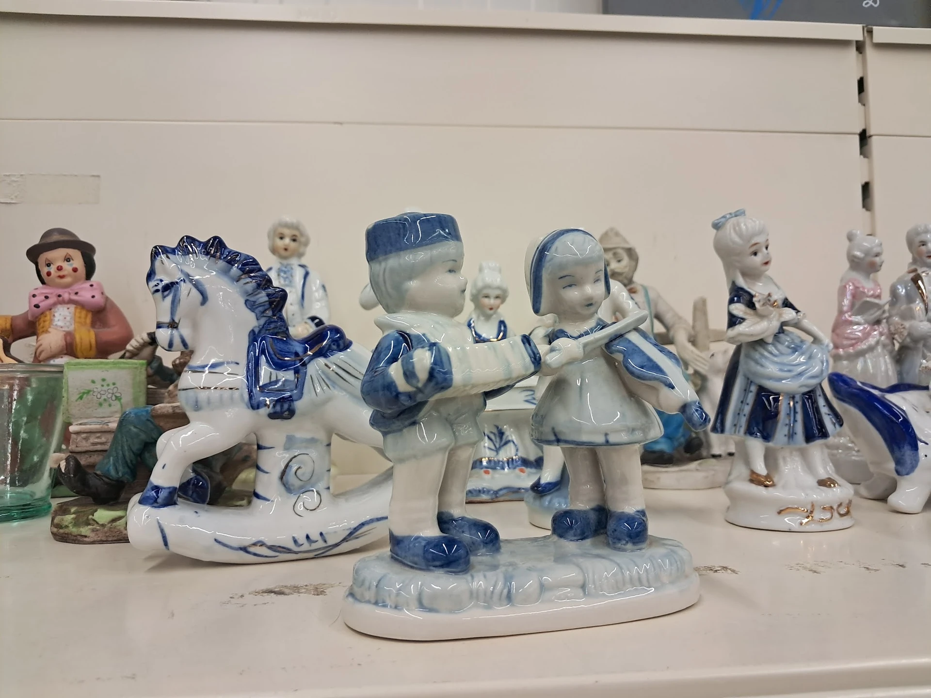 Verzameling decoratieve porseleinen beeldjes en figuren in blauw-wit, uitgestald op een plank
