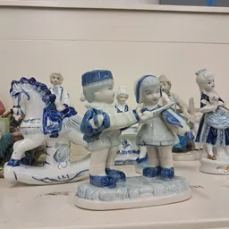 Verzameling decoratieve porseleinen beeldjes en figuren in blauw-wit, uitgestald op een plank