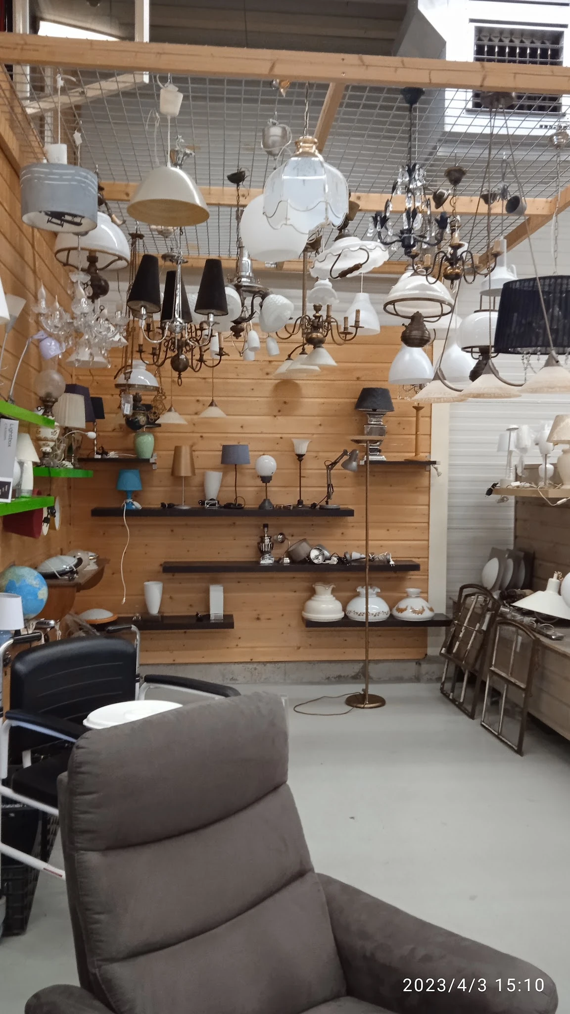 Wandkasten en planken met diverse lampen, lampenkappen en huishoudelijke artikelen