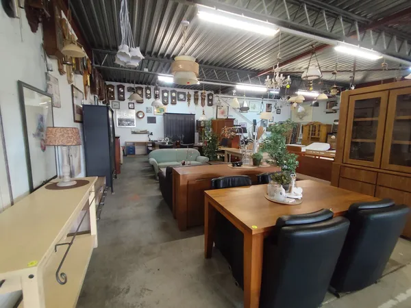 Winkelinterieur met houten meubels, eettafels, stellingen en wanddecoratie onder industrieel plafond