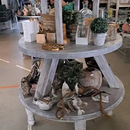 Ronde grijze tafel met decoratieve items en potplanten, onderplank met manden en plantenschalen