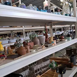 Stellingen met tweedehands huishoudartikelen, servies, keramiek en decoratieve objecten in een kringloopwinkel