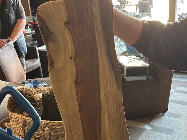 Close-up van een houten meubel (mogelijk tafel of dressoir) met bruine houtnerf en organische vormen