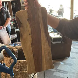 Close-up van een houten meubel (mogelijk tafel of dressoir) met bruine houtnerf en organische vormen