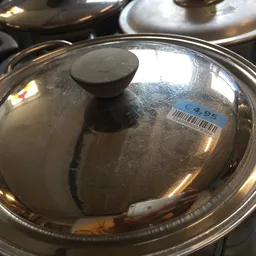 Glimmende metalen deksel met knop op een pannetje, gezien van bovenaf