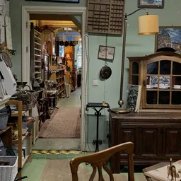 Binnenaanzicht van kringloopwinkel met stellingen, meubels en diverse tweedehands spullen langs de wanden