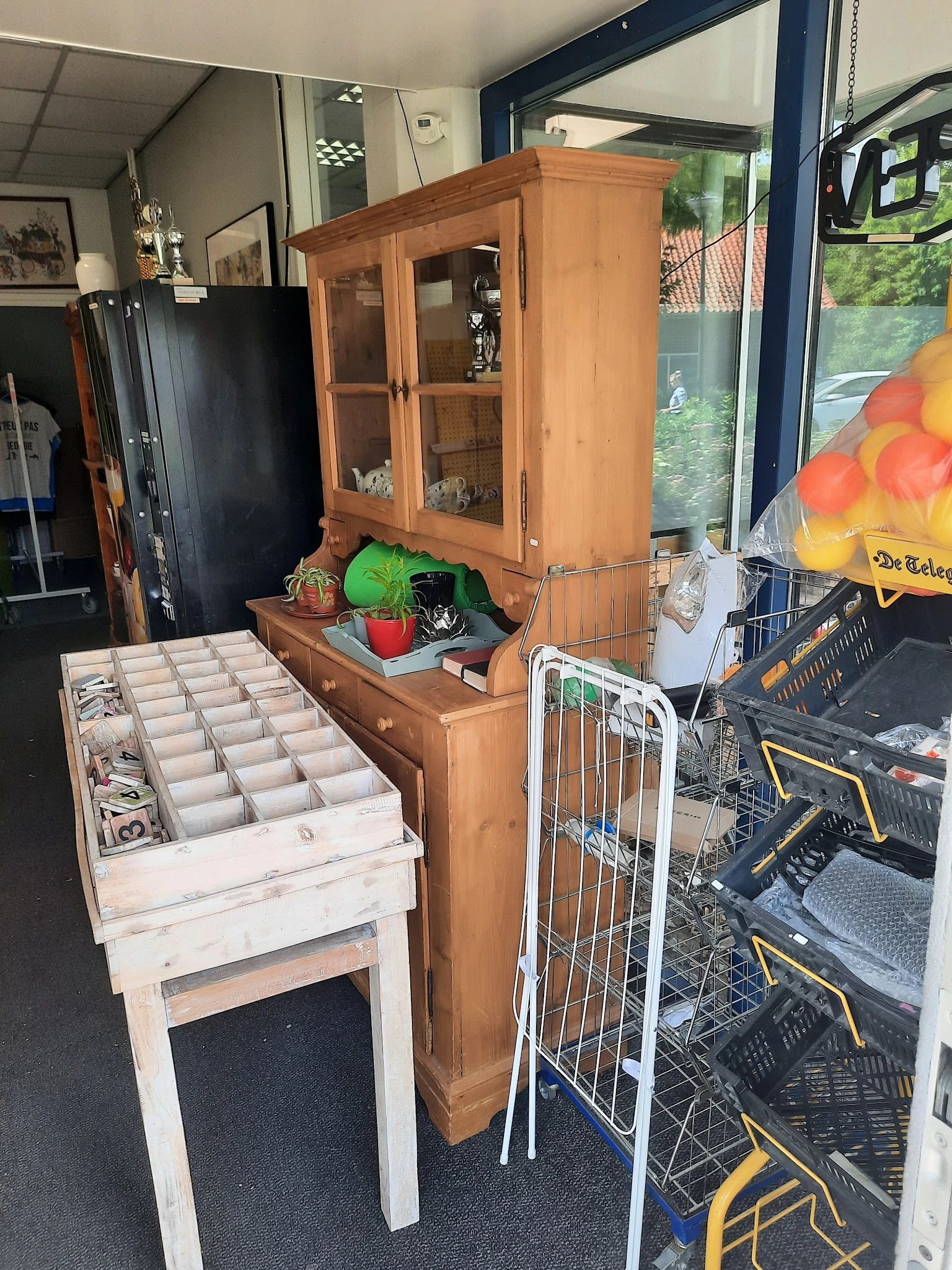 Binnenaanzicht van kringloopwinkel met houten meubels, opbergboxen en diverse spullen